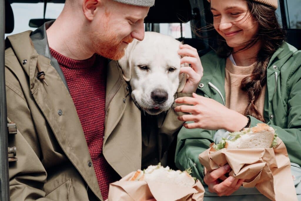 junges Paar ist Sandwich am Autobahn-Rasthof mit ihrem Labrador